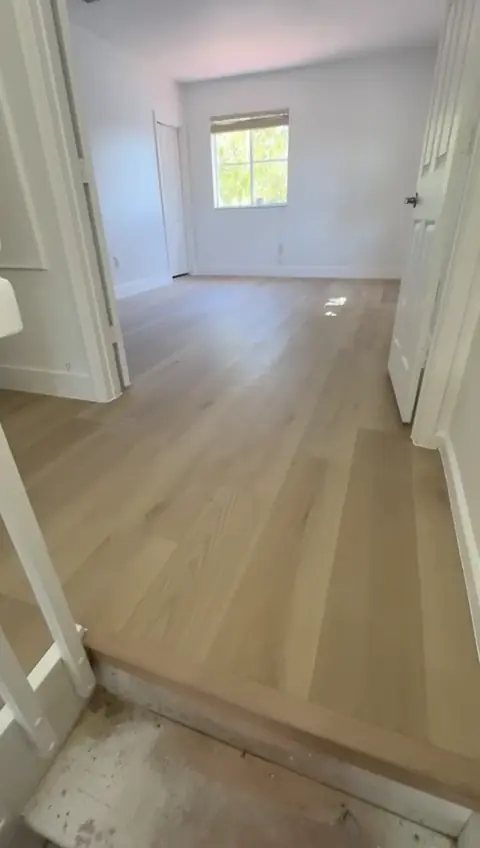 Fortified Wood vinyl plank from the Blue Armor line, installed by Ozzifloors in a Fort Lauderdale bedroom, with the bare slab still showing at the doorway in the foreground